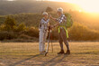 © pucko_ns - Mature couple walking in nature with backpack at the sunset at background
