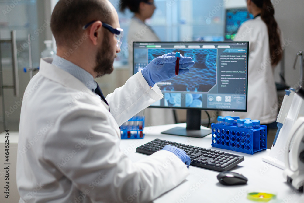 Biologist researcher man holding blood vacutainer analyzing dna sample ...