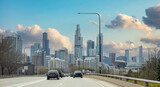 Fototapeta  - Chicago Illinois, USA. Cars on the road driving to Chicago city, high rise buildings and cloudy sky background