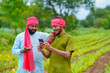 © Niks Ads - Indian farmer using smartphone at green turmeric agriculture field.