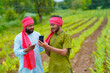© Niks Ads - Indian farmer using smartphone at green turmeric agriculture field.
