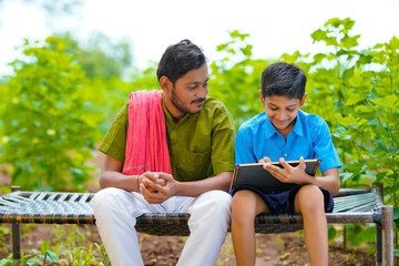 Wall Mural - Cute indian farmer child studying with his father at home