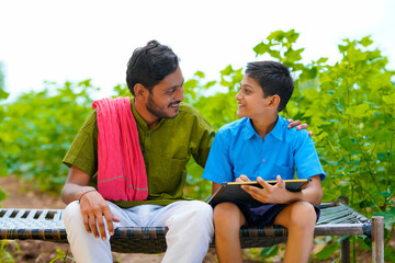 Wall Mural - Cute indian farmer child studying with his father at home