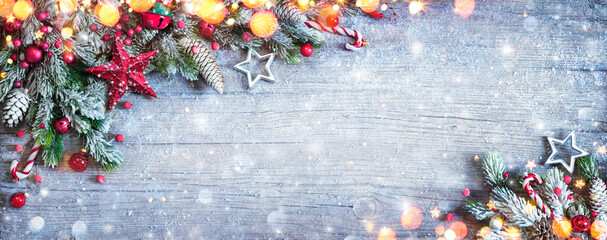 christmas decoration - ornament with fir branches and snow on blue wooden table with defocused light