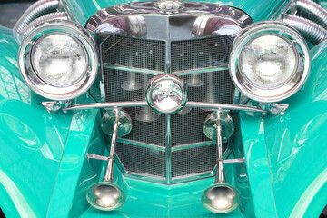 Front part of retro car with chrome radiator grille and beautiful round headlights