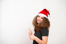 Happy Woman With Curly Hair In Santa Claus Christmas Hat Showing Thumb Up Sign On White Background