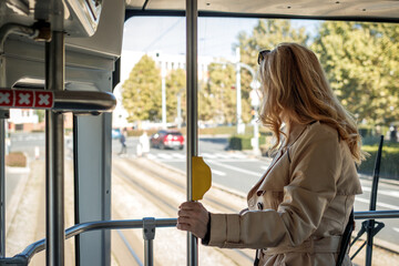 Woman commuting to work by tramway. Public transportation in city. Female commuter in tram looking through window to street