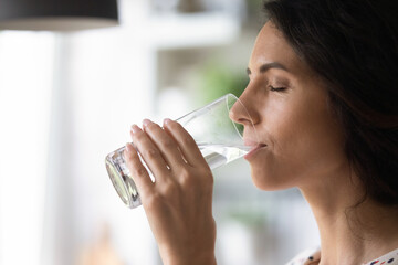 Peaceful woman satisfying thirst, drinking fresh pure clear cold water, enjoying beverage with closed eyes, keeping healthy hydration, aqua balance, diet, losing weight, practicing detox