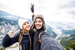 Traveler couple with backpacks taking selfie portrait hiking mountains - Happy guy and girl having fun outdoors