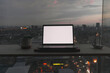 © Sevendeman - Laptop on wooden desk at the balcony with evening sunset city view.