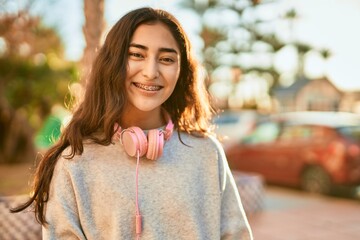 Wall Mural - Young middle east girl smiling happy using headphones at the city.