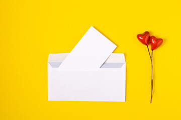 top view love letter, white envelope and card with red hearts on yellow background. white letter with copy space flat lay