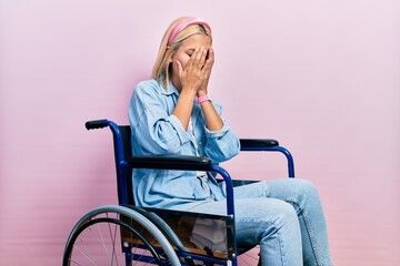 Poster - Beautiful blonde woman sitting on wheelchair with sad expression covering face with hands while crying. depression concept.