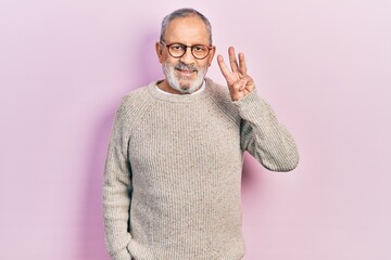 Sticker - Handsome senior man with beard wearing casual sweater and glasses showing and pointing up with fingers number three while smiling confident and happy.