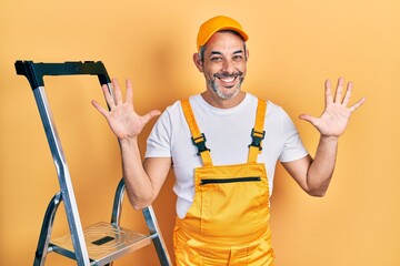 Sticker - Handsome middle age man with grey hair holding ladder showing and pointing up with fingers number ten while smiling confident and happy.