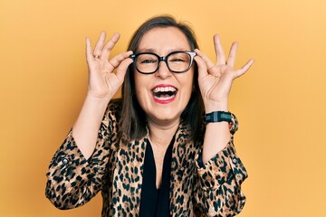 Wall Mural - Middle age hispanic woman wearing business clothes and holding glasses smiling and laughing hard out loud because funny crazy joke.