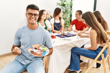 Canvas Print - Young artist man drawing at art studio looking positive and happy standing and smiling with a confident smile showing teeth