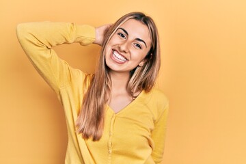 Canvas Print - Beautiful hispanic woman wearing casual yellow sweater smiling confident touching hair with hand up gesture, posing attractive and fashionable