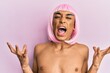 Hispanic transgender man wearing make up and pink wig crazy and mad shouting and yelling with aggressive expression and arms raised. frustration concept.