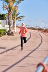 Wall Mural - Healthy sporty woman wearing hijab jogging outdoors