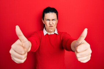 Poster - Young hispanic woman doing thumbs up positive gesture skeptic and nervous, frowning upset because of problem. negative person.