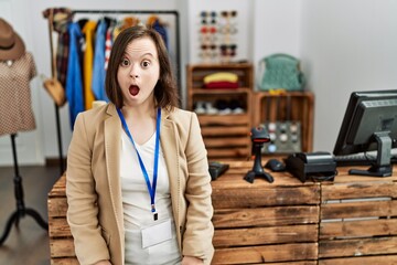 Wall Mural - Young down syndrome woman working as manager at retail boutique afraid and shocked with surprise expression, fear and excited face.