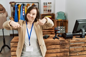 Canvas Print - Young down syndrome woman working as manager at retail boutique looking confident with smile on face, pointing oneself with fingers proud and happy.