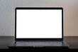 © 1take1shot - Empty laptop screen perfect for testing and a mockup of a design. Bright white screen in a dark environment. Device standing on a black wooden desk in front of a white wall.