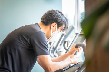 エアロバイクで運動する男性（マスク）
