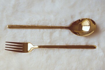 Elegant gold cutlery on a white wool surface.