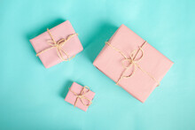 Gift Boxes Wrapped In Pink Kraft Paper And Tied With Twine Line On A Blue Background. Christmas Concept
