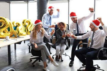 Wall Mural - Business people are celebrating holiday in modern office drinking champagne and having fun in coworking. Merry Christmas and Happy New Year 2022.