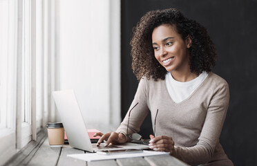 Wall Mural - Young woman using laptop computer at office. Student girl working at home. Work or study from home, freelance, business, lifestyle concept.