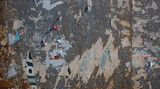 Fototapeta  - Old billboard with torn and worn posters. Dirty and rusty street wall with remains of posters. Abstract vintage background and texture.