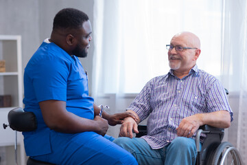 Caregiver and old man in a wheelchair. Professional nurse and patient in a nursing home. Assistance, rehabilitation and health care.