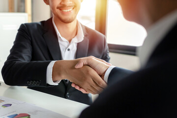 Wall Mural - Partnership. business people shaking hand after business signing contract and resume on desk in meeting room at company office, job interview, investor, negotiation, partnership and teamwork concept