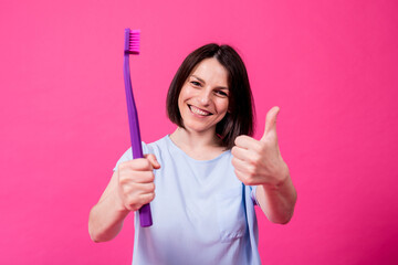 Wall Mural - Beautiful happy young woman with big toothbrush on blank pink background