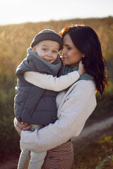 mother and her son are standing in a field with dry grass at sunset