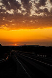Fototapeta Dziecięca - Incredibly beautiful sunset in the countryside. Bright peach and orange sunset and cumulus clouds in the sky. Sunset on the highway on which cars drive