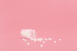 Close-up image of homeopathic globules in glass bottle on pastel pink background. Homeopathy pharmacy, herbal, natural medicine, alternative homeopathy medicine, healthcare. Free space, copy space.