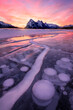 Stunning sunrise with trapped frozen methane bubbles within ice surface, Lake Abraham, Alberta. Winter storm in Canada.