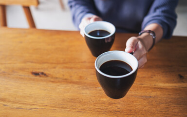 Closeup image of a woman holding and serving two cups of coffee