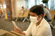 © smolaw11 - Asian Senior Traveler with New Normal in protecting face mask using smartphone for online social media reading news and searching check in flight timetable at airport terminal. Safe travel in COVID-19