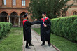 © Тарас Нагирняк - Two graduate friends greeting in university campus in graduation gowns