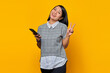© Bangun Stock Photo - Beautiful Asian woman holding smartphone smiling and showing peace sign over yellow background