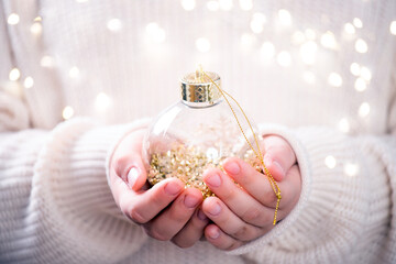 Golden Christmas ball in hands of a little girl. Christmas card