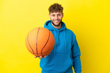 Young handsome caucasian man isolated on yellow background playing basketball