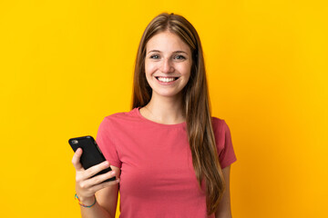 Sticker - Young woman using mobile phone isolated on yellow background smiling a lot