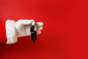 Santa claus holding car key on red background, copy space