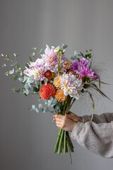 a woman is holding a festive bouquet with chrysathemum flowers in her hands.